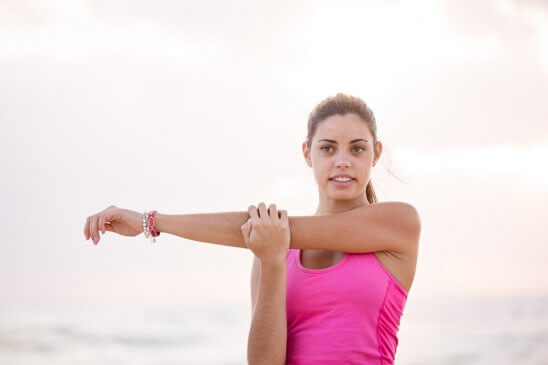 woman in pink tank top stretching arm