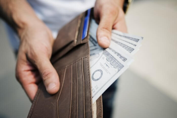Man holding brown leather wallet with money