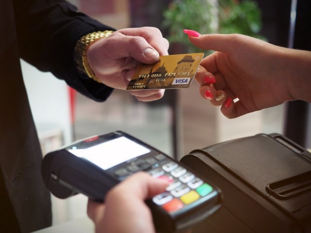Photo of person handing credit card for payment process